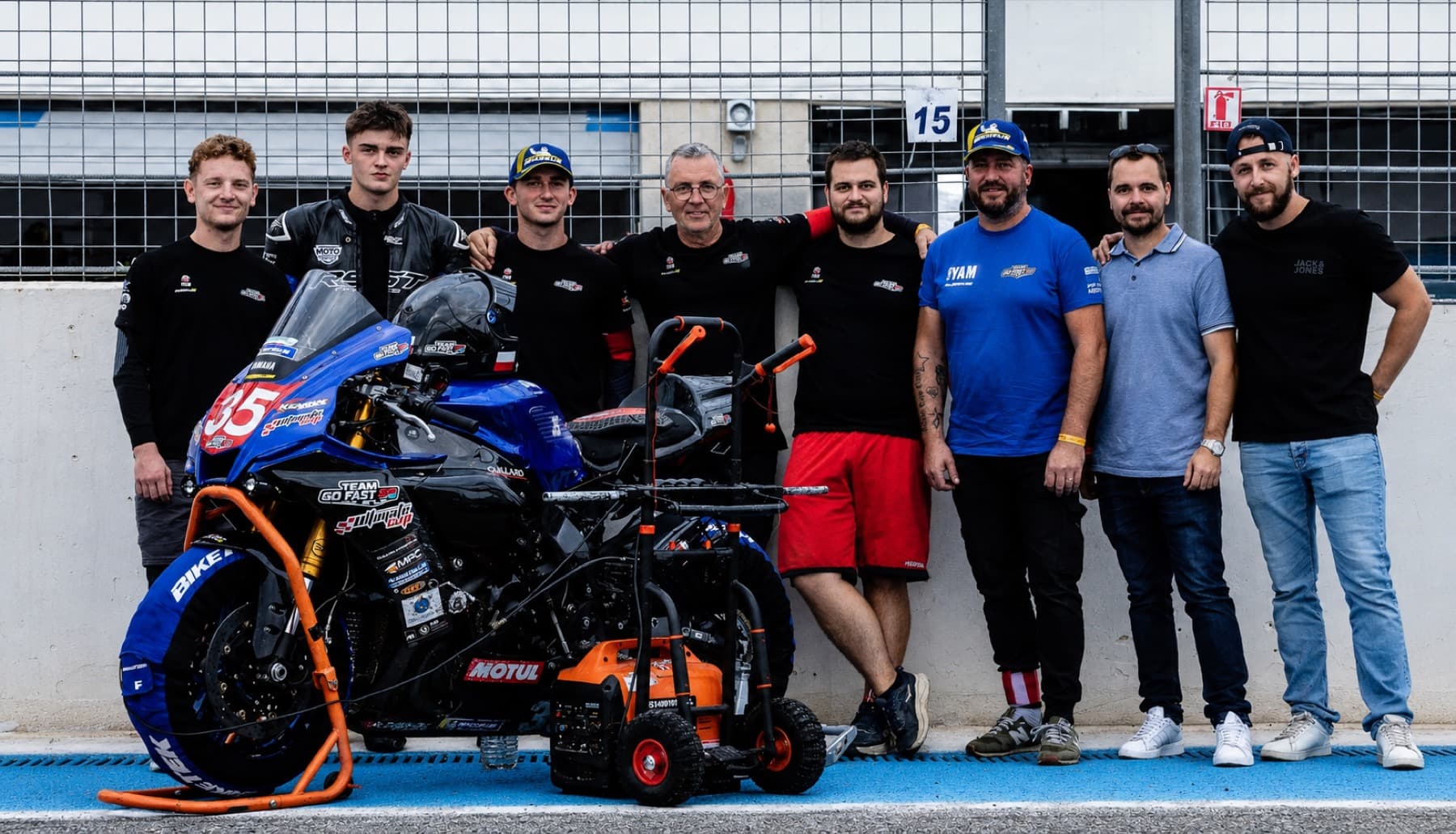 L'équipe Go Fast 35 réunie devant la moto numéro 35, dans la voie des stands du circuit Paul Ricard